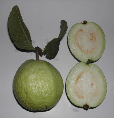 A green guava, whole and halved to show its pale flesh