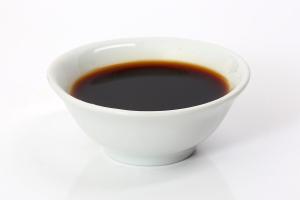 A white bowl of dark soy sauce